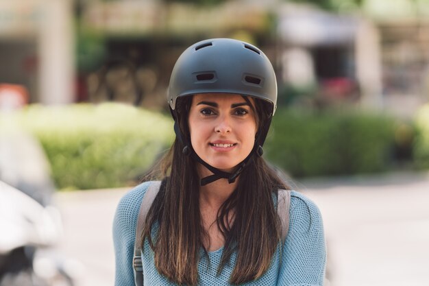 Portret van een jonge vrouw met een fietshelm die naar de camera op straat kijkt