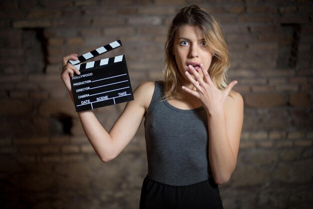 Foto portret van een jonge vrouw met een filmschijf terwijl ze tegen een bakstenen muur staat