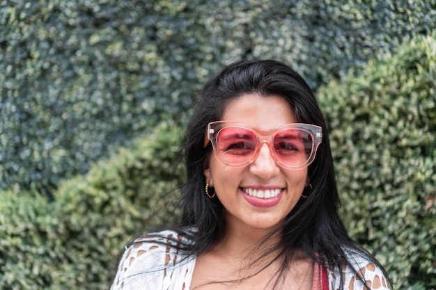Portret van een jonge vrouw met een glimlach en een zonnebril in de stad