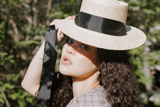 Portret van een jonge vrouw met een hoed die in het park zit