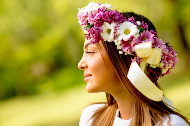 Foto portret van een jonge vrouw met een krans van verse bloemen op het hoofd in het park