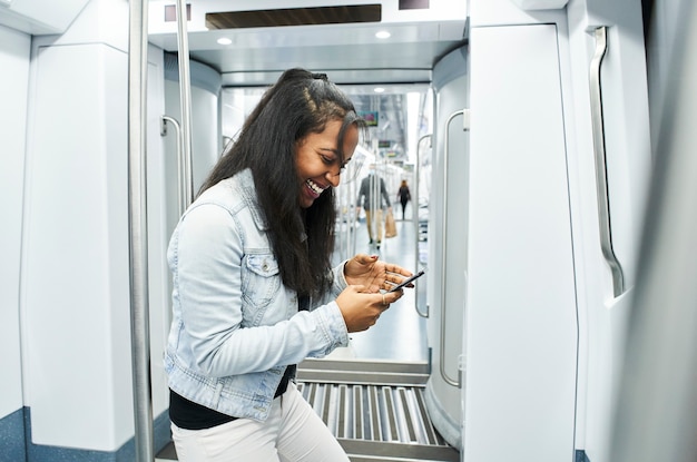 Portret van een jonge vrouw met een masker die haar celtelefoon in de metroauto gebruikt.