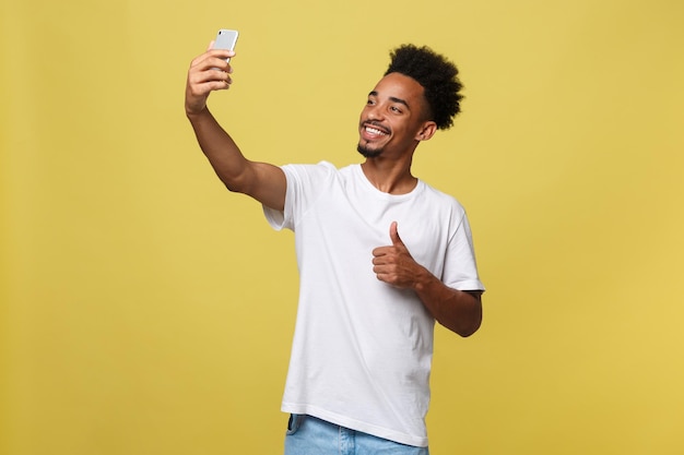 Portret van een jonge vrouw met een mobiele telefoon terwijl ze tegen een gele achtergrond staat