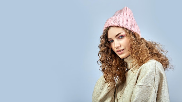 Portret van een jonge vrouw met een roze hoed op een grijze achtergrond