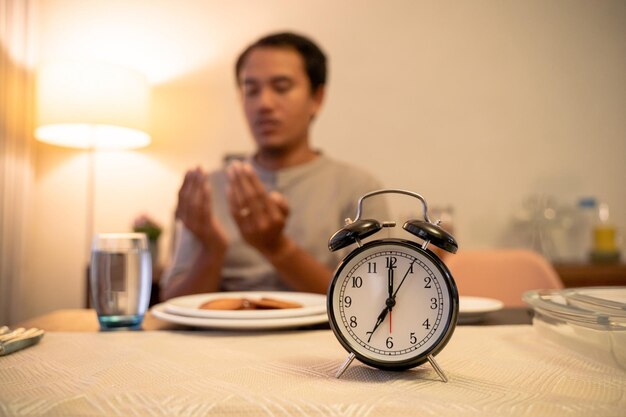 Portret van een jonge vrouw met een wekker op tafel