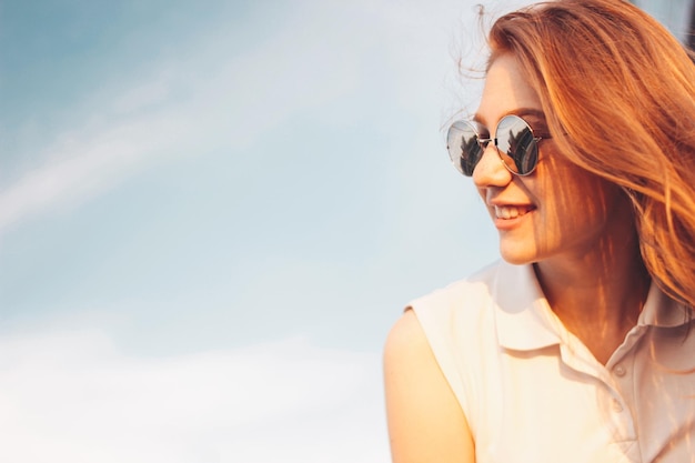 Foto portret van een jonge vrouw met een zonnebril tegen de lucht