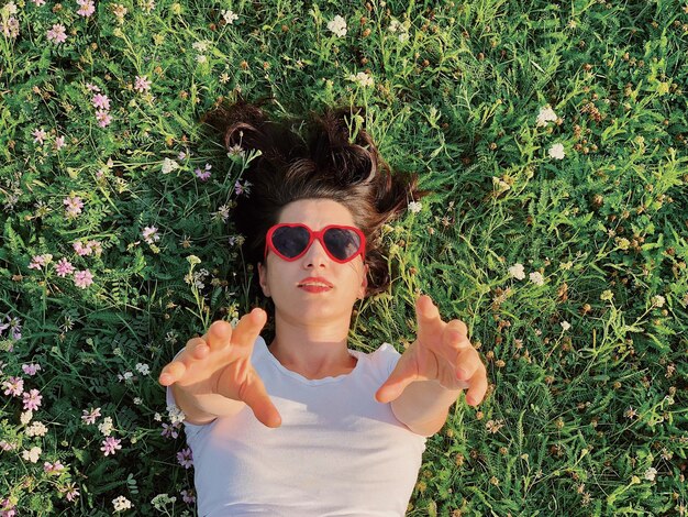 Foto portret van een jonge vrouw met een zonnebril tegen planten