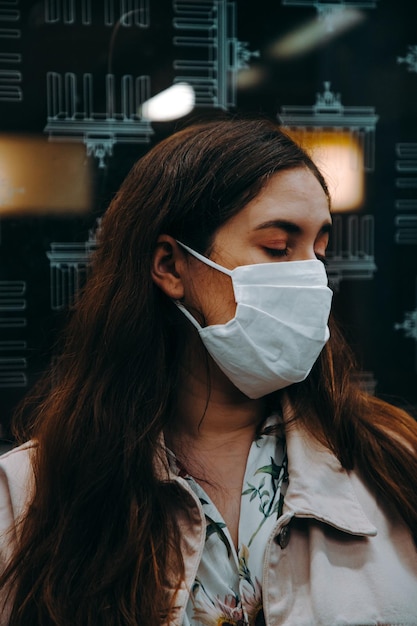 Portret van een jonge vrouw met gesloten ogen die een gezichtsmasker draagt in een ondergrondse trein