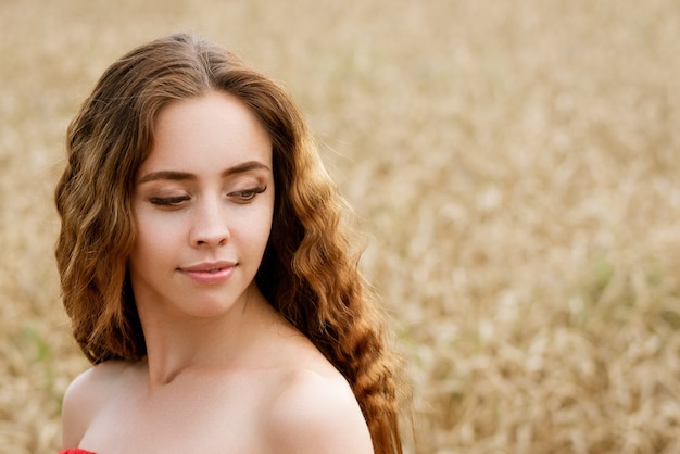 Portret van een jonge vrouw met golvend haar in een veld met tarwe. natuurlijke cosmetica concept