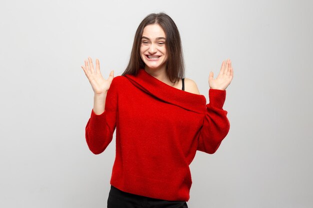 Portret van een jonge vrouw met heldere positieve emoties op een lichtgrijze achtergrond Foto lacht meisjes