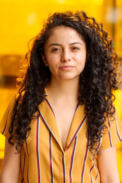 Portret van een jonge vrouw met krullend haar op gele achtergrond