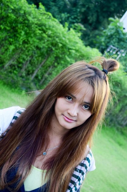 Foto portret van een jonge vrouw met lang bruin haar in het park