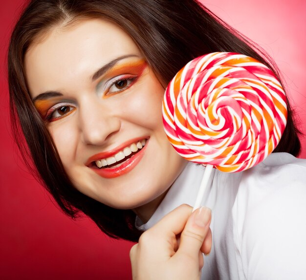 Portret van een jonge vrouw met lolly op rood