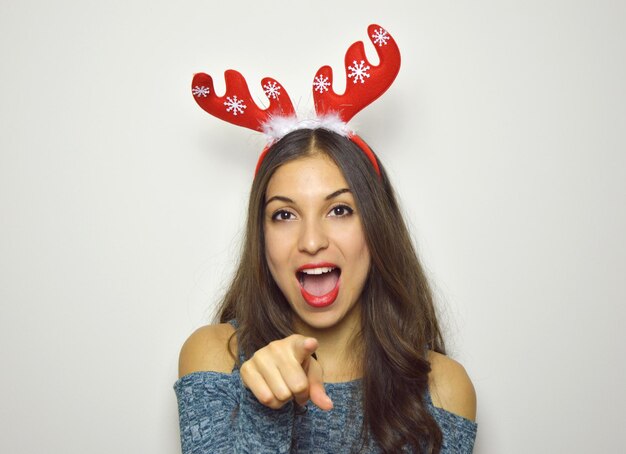 Foto portret van een jonge vrouw met open mond die een hoofdband draagt tijdens kerst op een witte achtergrond