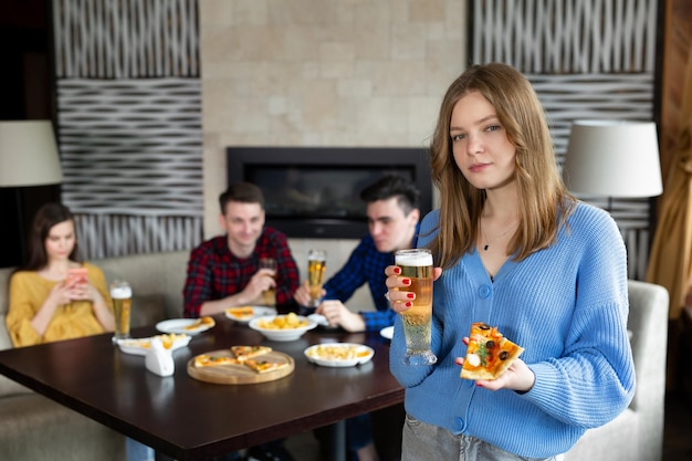 Portret van een jonge vrouw met pizza en bier in een pub