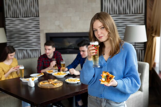 Portret van een jonge vrouw met pizza en bier in een pub