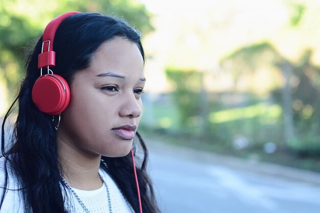 Portret van een jonge vrouw met rode koptelefoon luisteren muziek