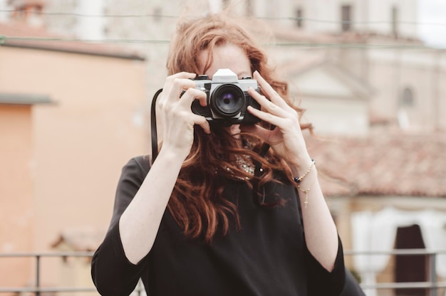Portret van een jonge vrouw met rood haar die fotografeert