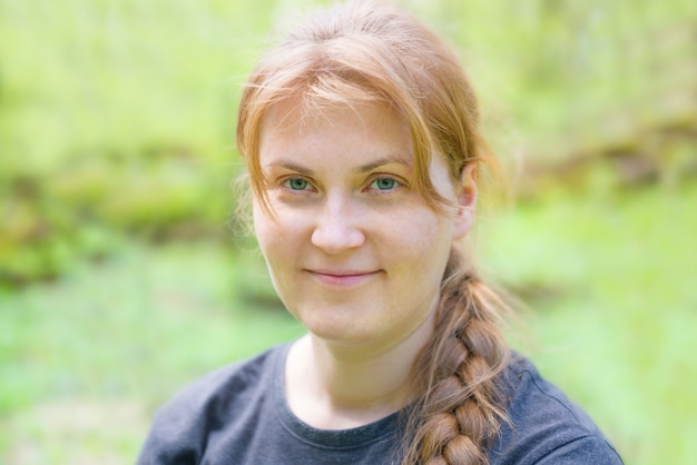 Portret van een jonge vrouw met rood haar en vlecht in het groene bos