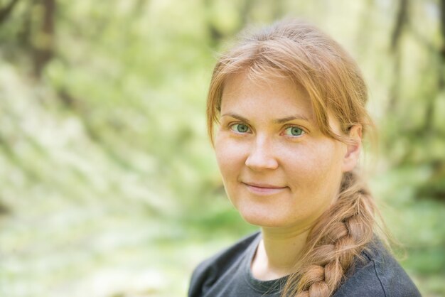 Portret van een jonge vrouw met rood haar en vlecht in het groene bos