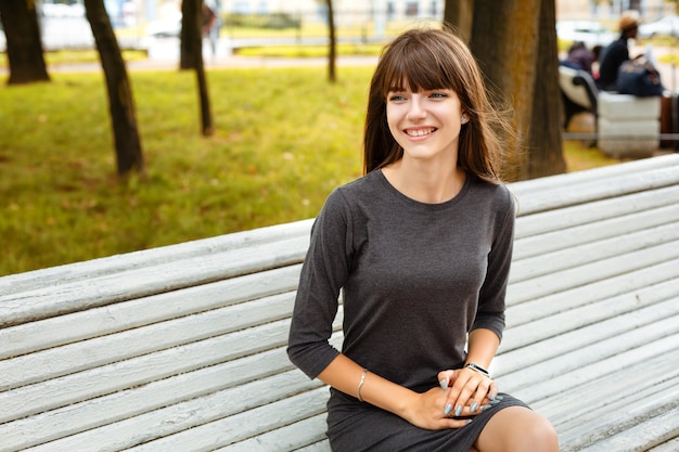 Portret van een jonge vrouw zitten in het park op een bankje