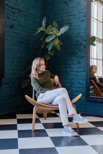 Foto portret van een jonge vrouw zittend op een stoel in een stijlvolle woonkamer