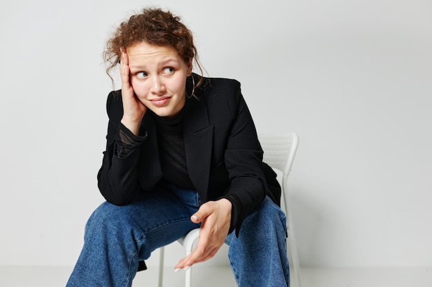 Portret van een jonge vrouw zwarte jas jeans poseren lichte achtergrond ongewijzigd