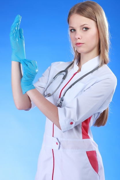 Portret van een jonge vrouwelijke arts met witte jas en blauwe handschoenen