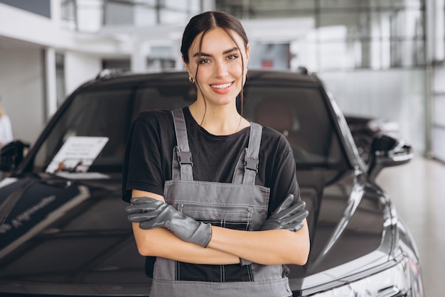 Portret van een jonge vrouwelijke professionele vrouwelijke monteur die naar de camera glimlacht in een auto-reparatiewinkel