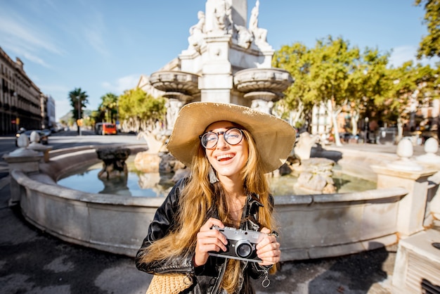 Portret van een jonge vrouwelijke toerist met een fotocamera die bij de fontein in de stad Barcelona staat