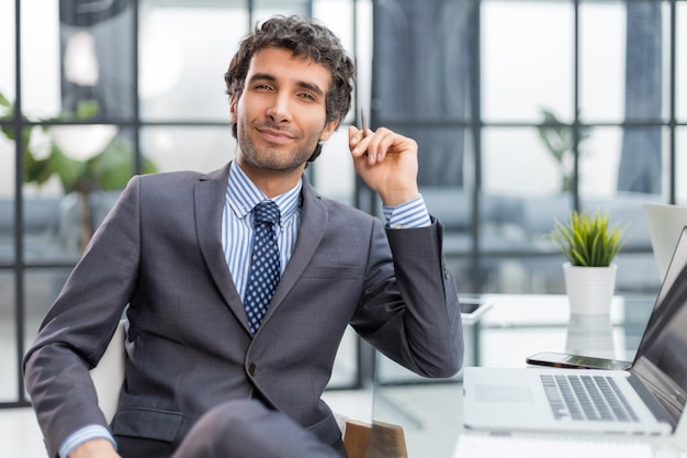 Portret van een jonge zakenman die aan zijn bureau zit op kantoor