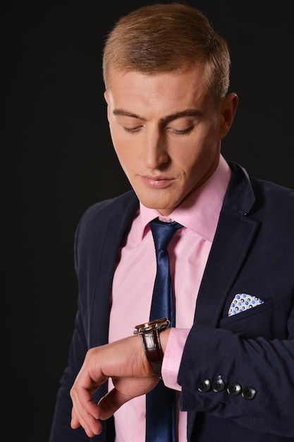 Portret van een jonge zakenman die de tijd controleert op het horloge