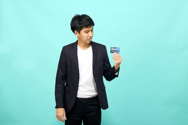 Portret van een jonge zakenman die een creditcard bij de hand houdt en toont op een geïsoleerde blauwe achtergrond