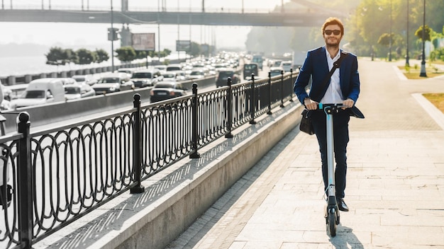 Portret van een jonge zakenman die een elektrische scooter berijdt op de weg in de stad