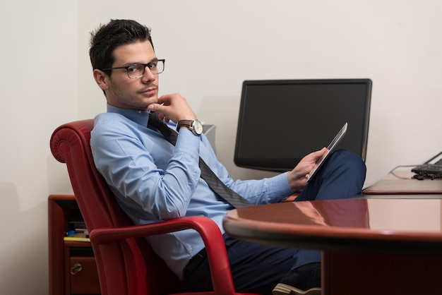 Portret van een jonge zakenman die een touchpad op kantoor gebruikt