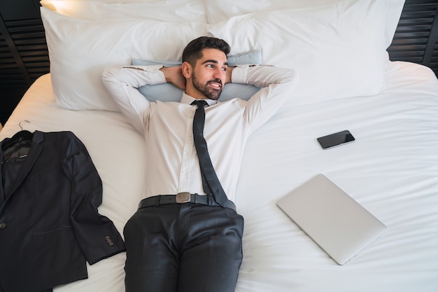 Portret van een jonge zakenman een pauze nemen van het werk en ontspannen na een dag hard in de hotelkamer. Zakelijke reizen concept.