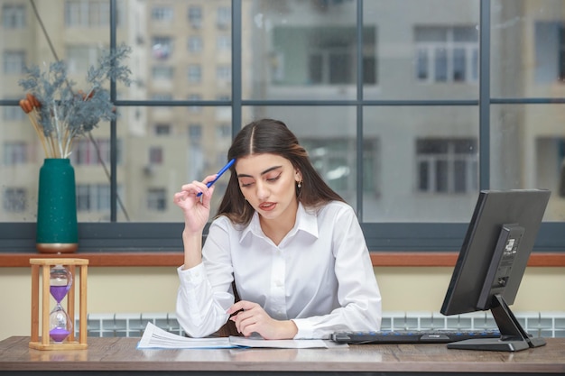 Portret van een jonge zakenvrouw die aan het bureau zit en denkt