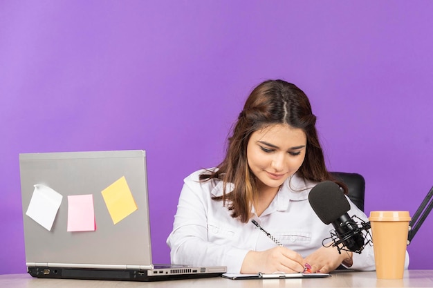 Portret van een jonge zakenvrouw die achter het bureau zit en haar aantekeningen maakt Foto van hoge kwaliteit