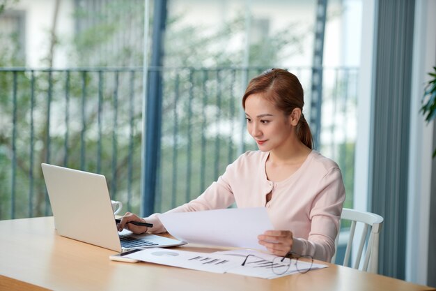 Portret van een jonge zakenvrouw die laptop op kantoor gebruikt