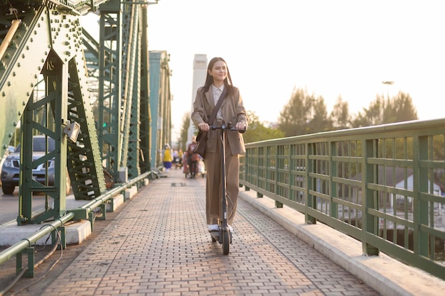 Portret van een jonge zakenvrouw met een elektrische scooter om over de brug te werken