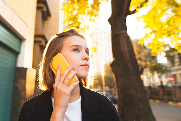 Portret van een jonge zakenvrouw praten op een smartphone een zonnige stad