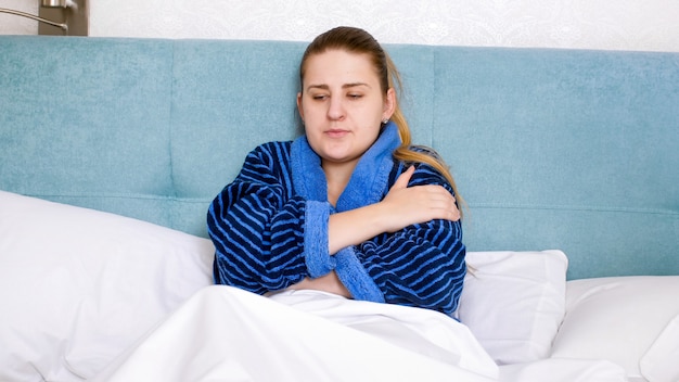 Portret van een jonge zieke vrouw die zich slecht voelt liggend in bed