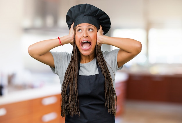 Portret van een jonge zwarte bakkersvrouw gefrustreerd en wanhopig, boos en droevig met handen op hoofd