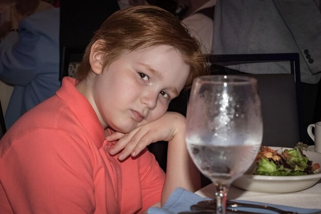 Foto portret van een jongen bij eten en drinken op tafel in een restaurant