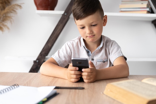 Portret van een jongen die aan de telefoon speelt of chat in een sociaal netwerk mobiel gadget Kinderverslaving Online- of internetgames Home-entertainmentconcept