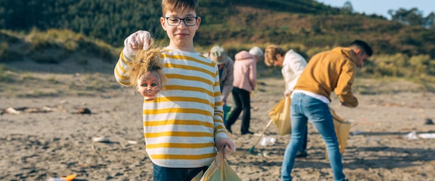 Foto portret van een jongen die afval vasthoudt terwijl hij op het strand staat