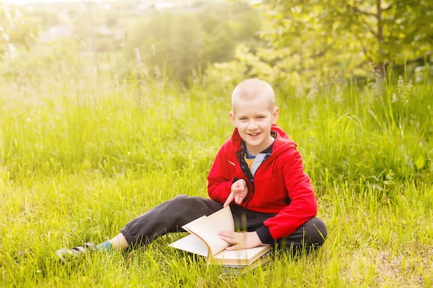 Portret van een jongen die met een boek in het park zit