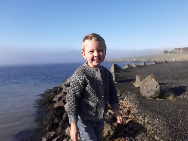 Foto portret van een jongen die op het strand staat