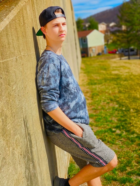 Foto portret van een jongen die tegen een muur staat