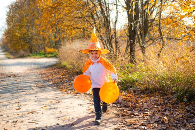 Portret van een jongen in Halloween-kleding met pompoenballonnen op straat Een traditionele feestdag 31 oktober
